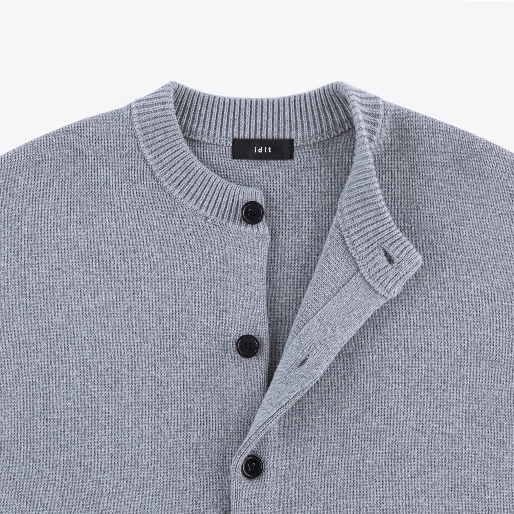 Close-up of ash gray wool blend knit cardigan crew neck ribbing and dark button front placket