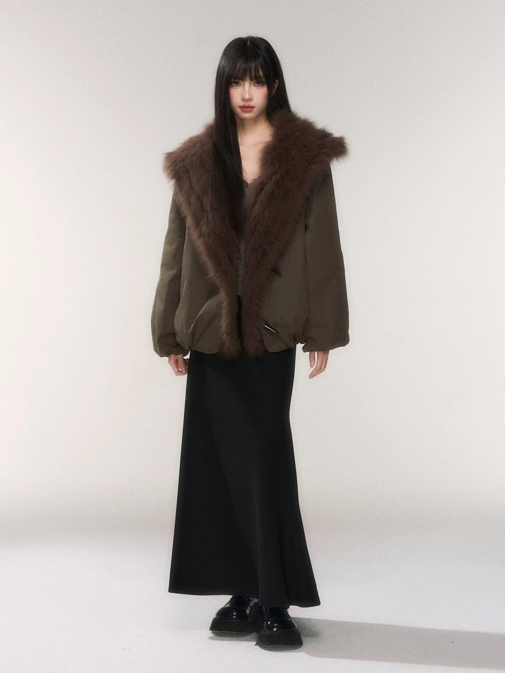Black minimalist knit fishtail maxi skirt styled with an olive cropped jacket with faux fur collar in a full body studio look