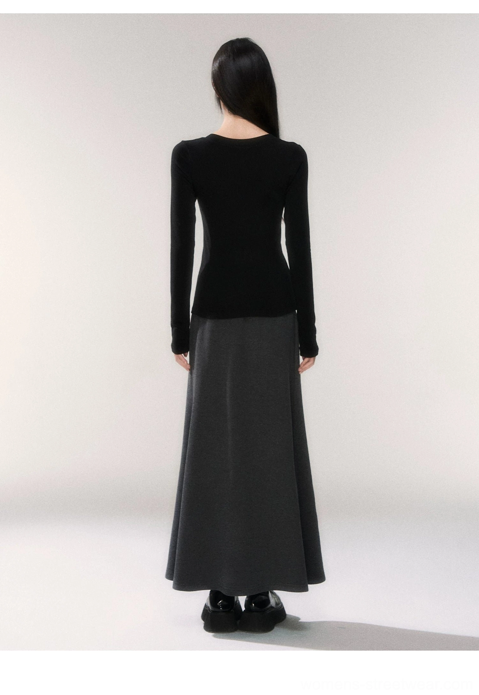 Back view of dark gray knit fishtail maxi skirt showing the long fitted silhouette and subtle flared hem with black fitted top