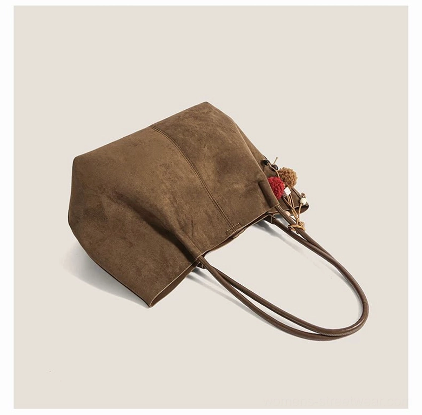 Minimalist suede look shoulder tote with yarn pom pom pendant, wooden bead details, and relaxed Seoul fashion aesthetic