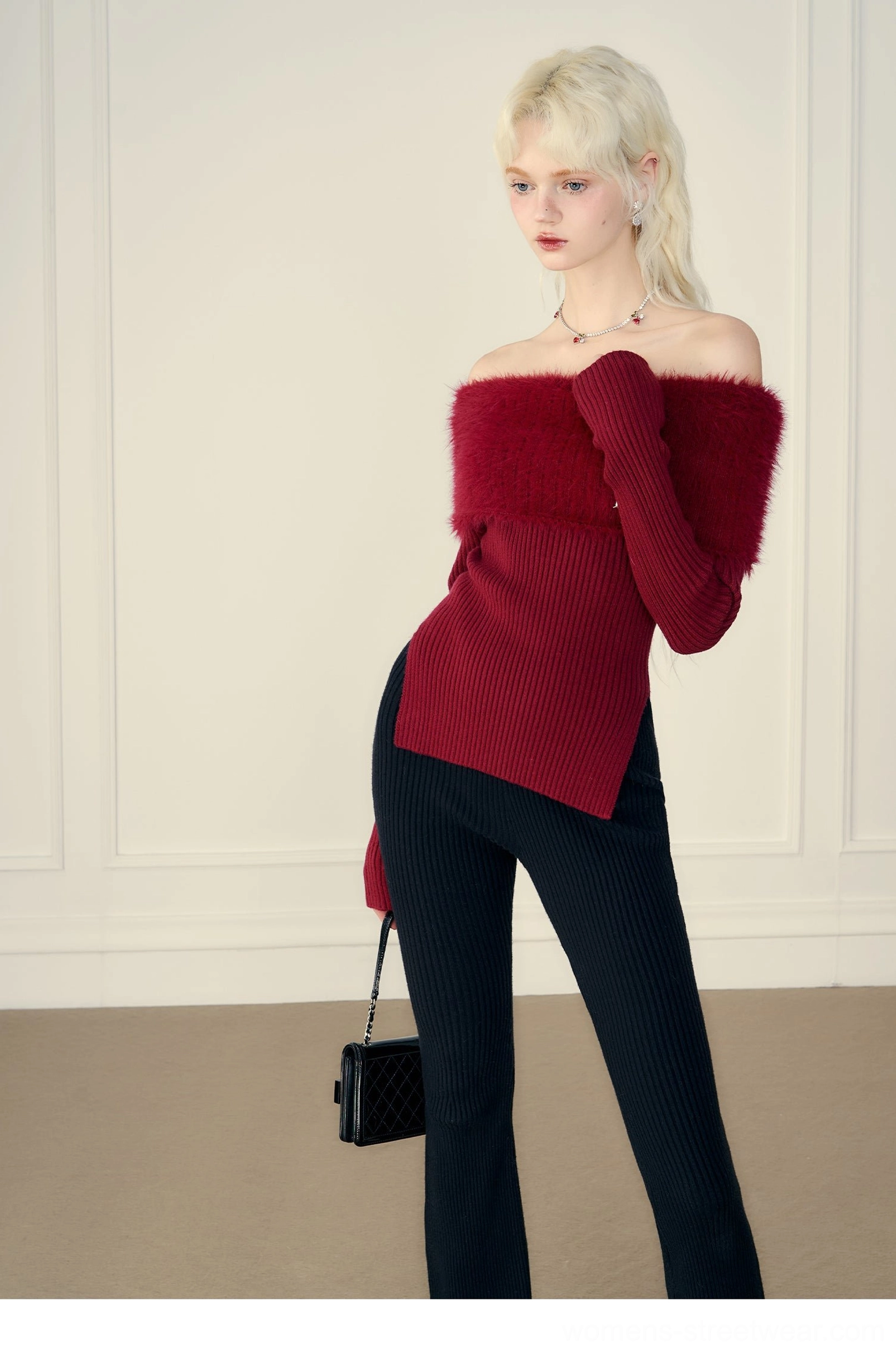 Side view of red off-shoulder fur trim knit sweater with long sleeves and split hem