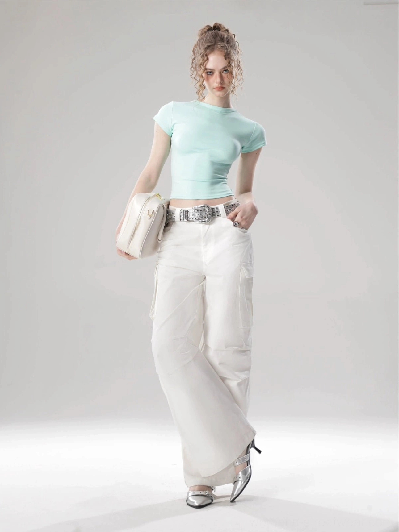 Mint green Korean streetwear cropped top styled with white wide-leg pants silver belt and beige shoulder bag