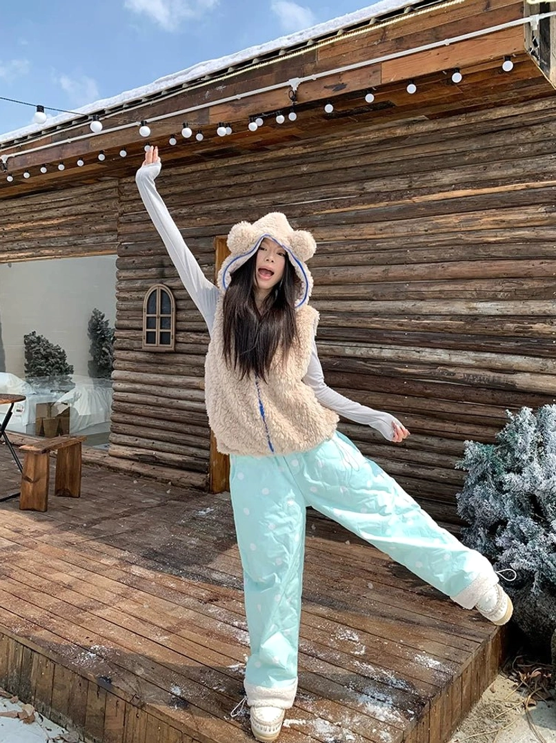 Mint green polka dot wide leg fleece cuff pants styled with a fuzzy bear ear vest in a snowy cabin setting