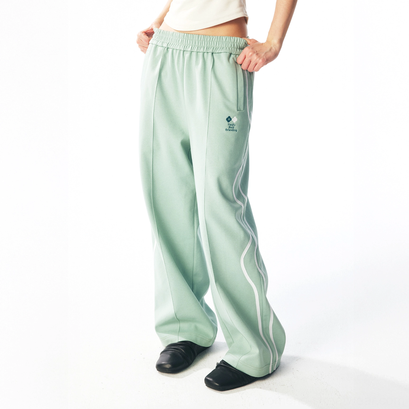 Mint green quick-dry streetwear track pants showing elastic waistband, side pockets, and curved stripe detail