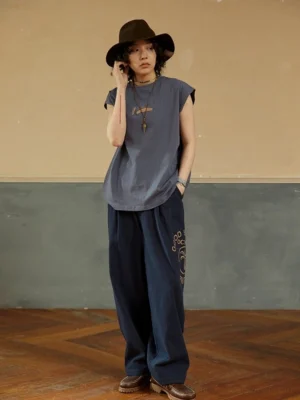 Misty Purple Blue minimalist cotton sleeveless tee worn with wide-leg denim, cowboy hat, and leather boots in a vintage streetwear studio look