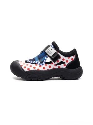 Left side studio view of mixed print trail sole Mary Jane sneakers with red polka dots blue plaid velcro strap and black rubber toe cap