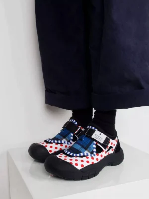 Top front view of mixed print trail sole Mary Jane sneakers worn with black socks and rolled wide leg pants