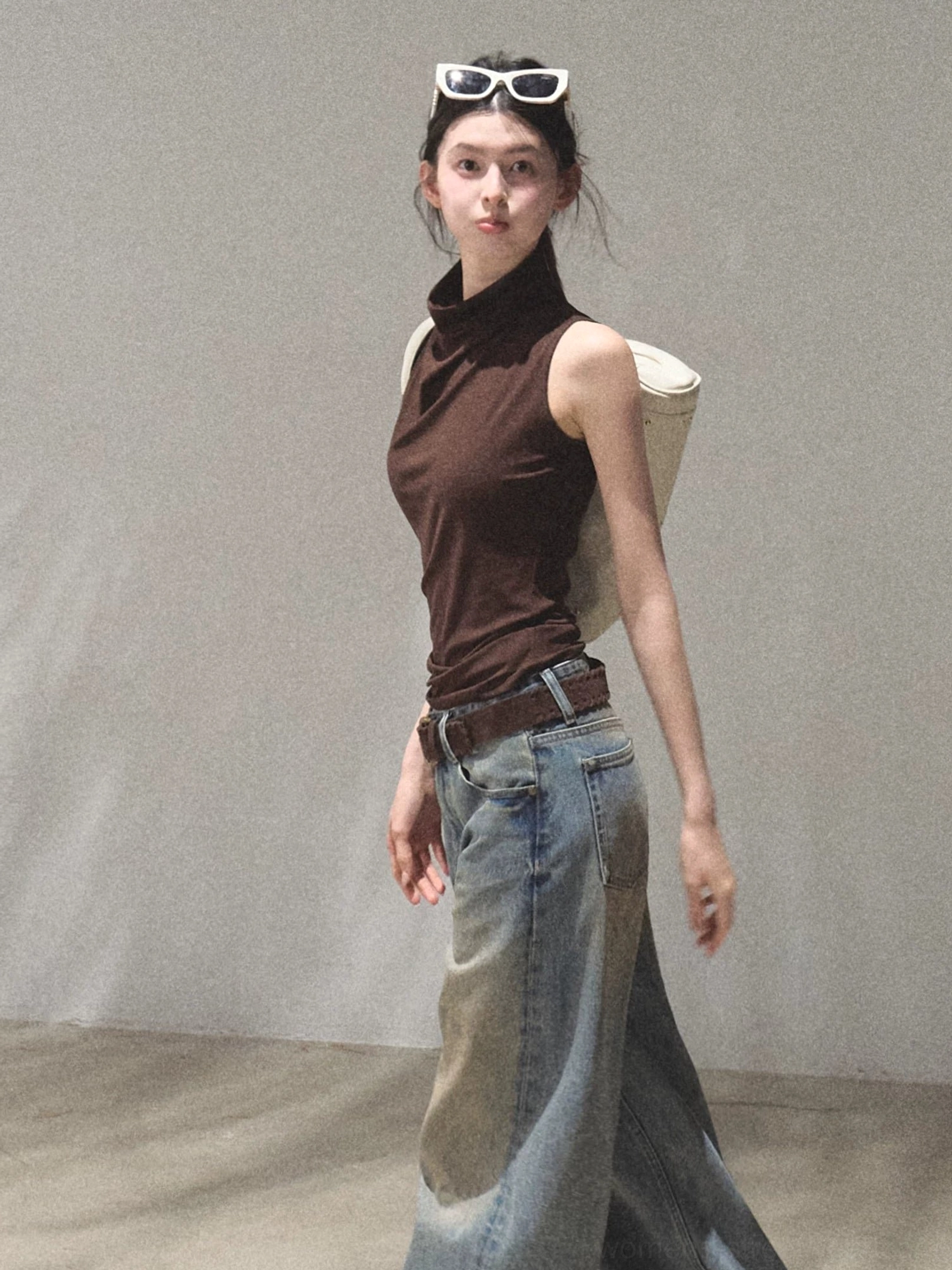 Side view of mocha draped mock neck sleeveless fitted streetwear top with vintage jeans