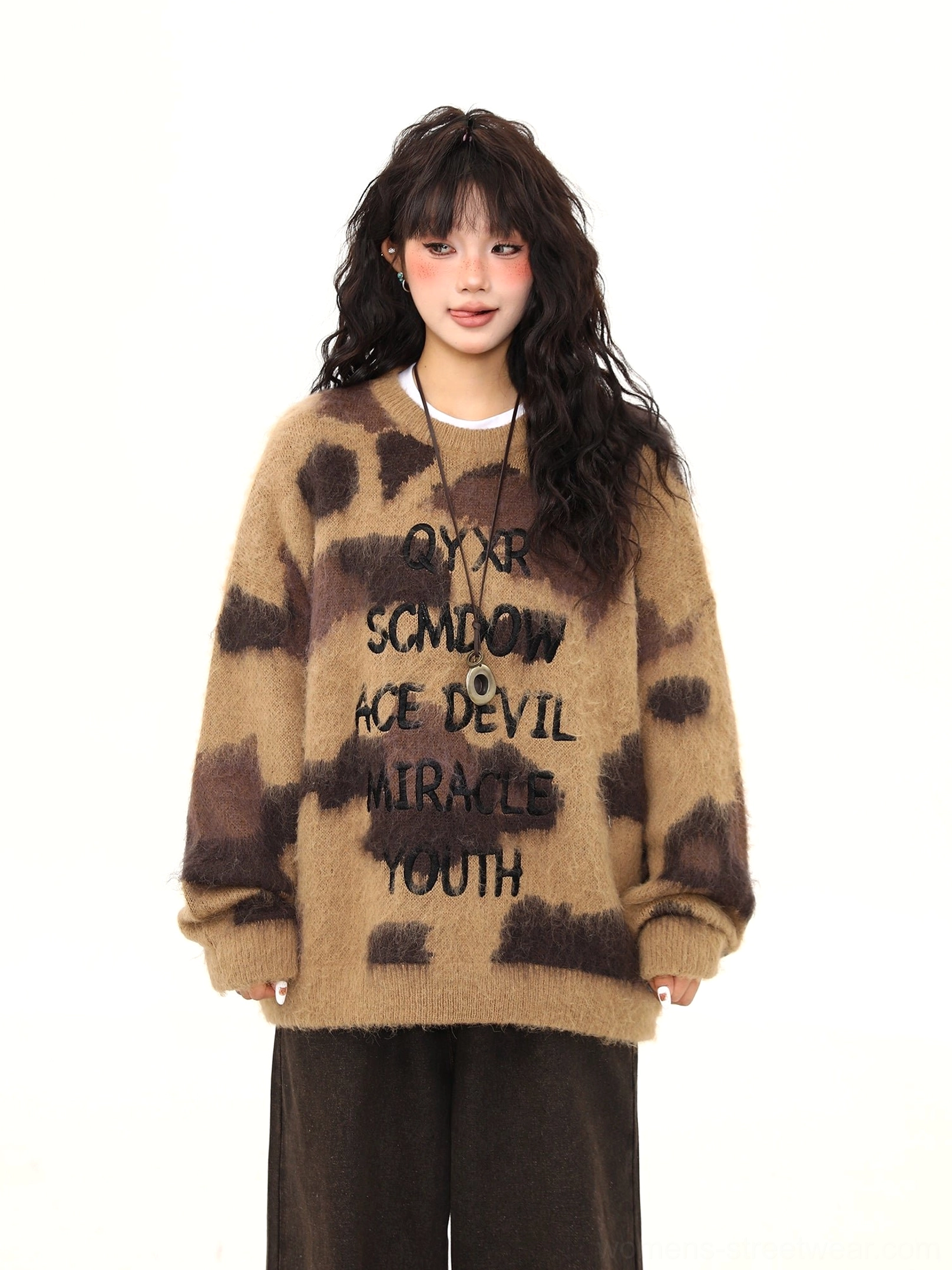 Front detail of mocha fuzzy graphic sweater showing black slogan lettering and blurred animal-inspired print