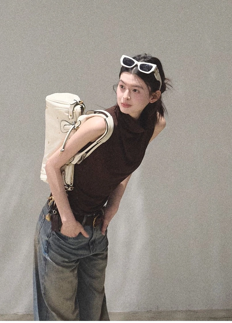 Mocha sleeveless draped mock neck fitted top side view with white shoulder bag