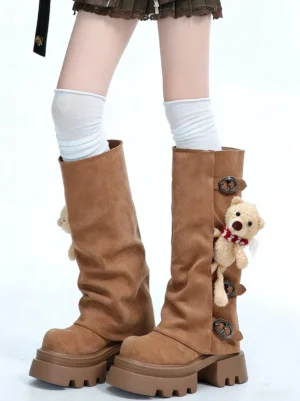 Model wearing brown teddy bear charm lug-sole mid-calf boots with white knee-high socks and slouchy shafts