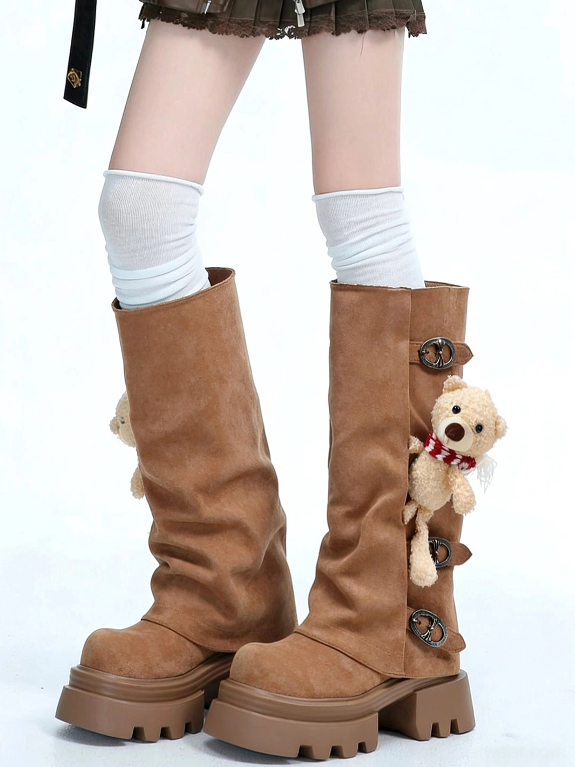 Model wearing brown teddy bear charm lug-sole mid-calf boots with white knee-high socks and slouchy shafts