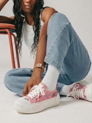 Black female model wearing pink graffiti platform sneakers with blue jeans and white crew socks