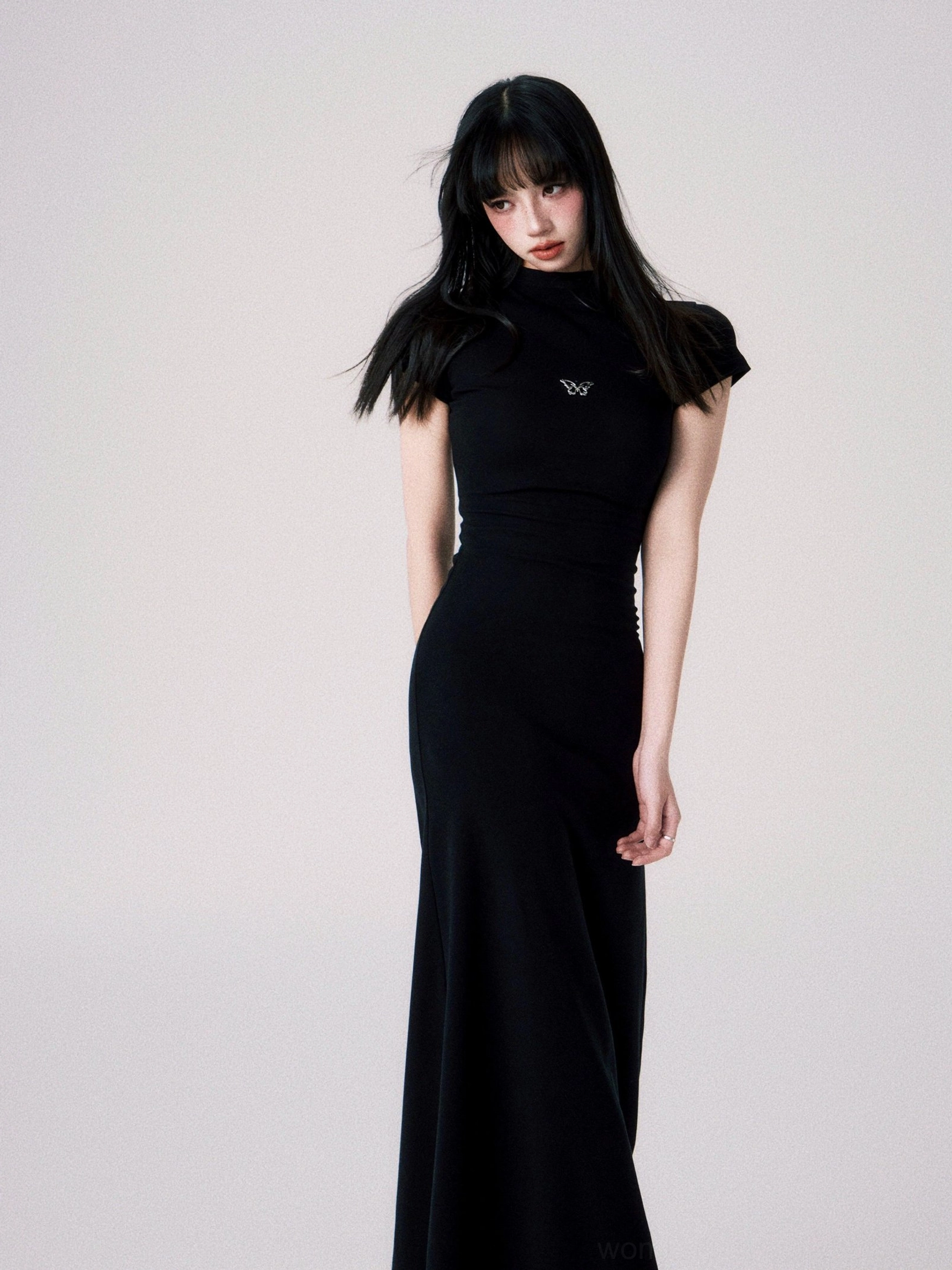 Modern fitted maxi dress with subtle butterfly chest emblem and elegant floor length streetwear silhouette