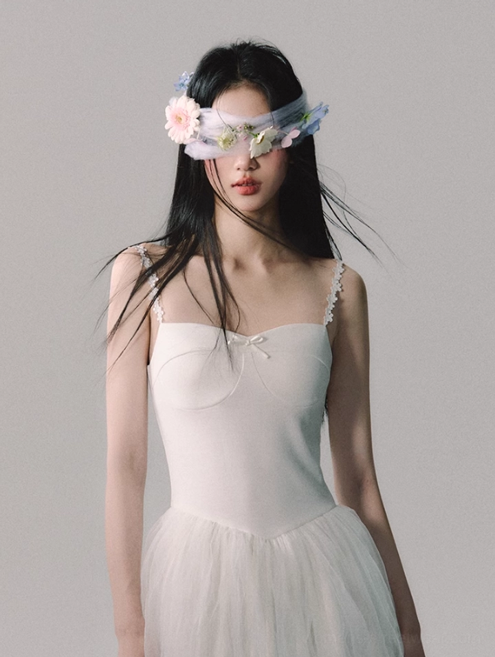Modern white bridal-style tulle gown with lace-trimmed spaghetti straps and ethereal floor-length silhouette