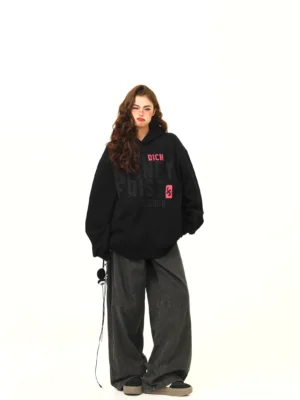 Money First oversized black graphic streetwear hoodie front view styled with grey wide-leg pants