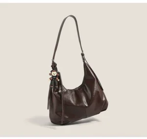 Brown faux-leather monkey charm hobo bag shown in a three-quarter front view with a relaxed slouchy crescent silhouette