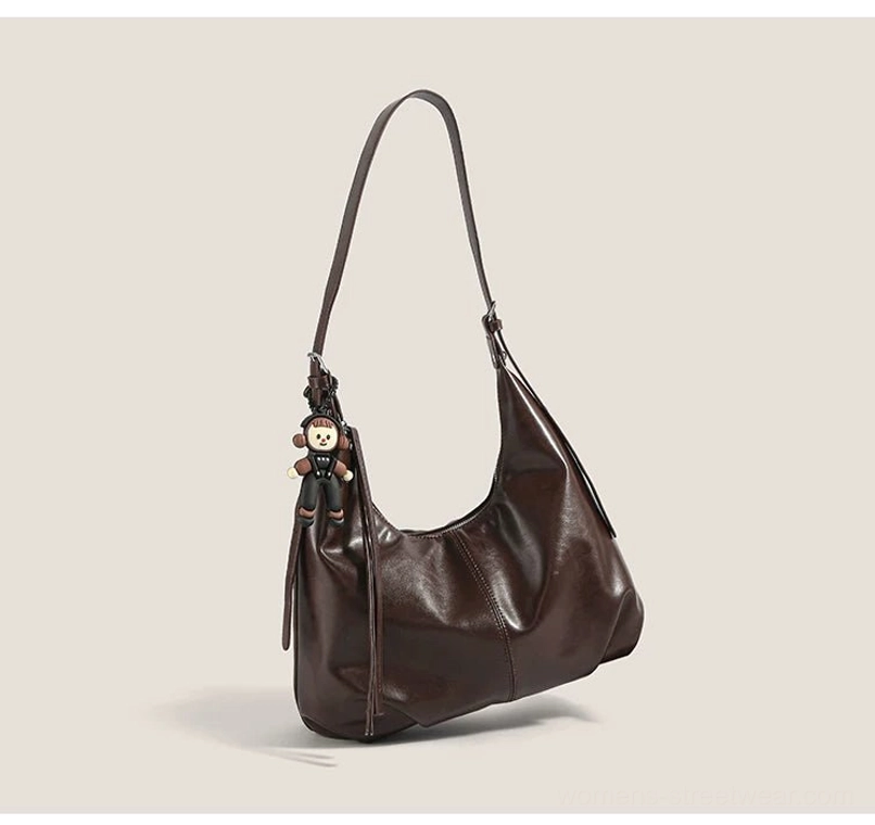 Brown faux-leather monkey charm hobo bag shown in a three-quarter front view with a relaxed slouchy crescent silhouette