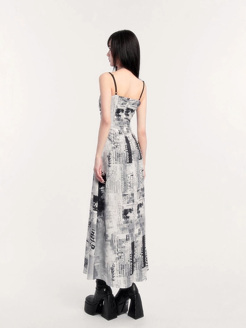 Back view of long newspaper print slip dress with open back, black spaghetti straps, and flowing maxi skirt