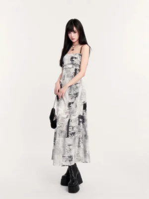 Three quarter front view of newspaper print slip maxi dress with ruched bodice, black handbag, and platform boots