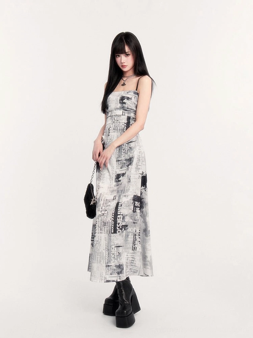 Three quarter front view of newspaper print slip maxi dress with ruched bodice, black handbag, and platform boots