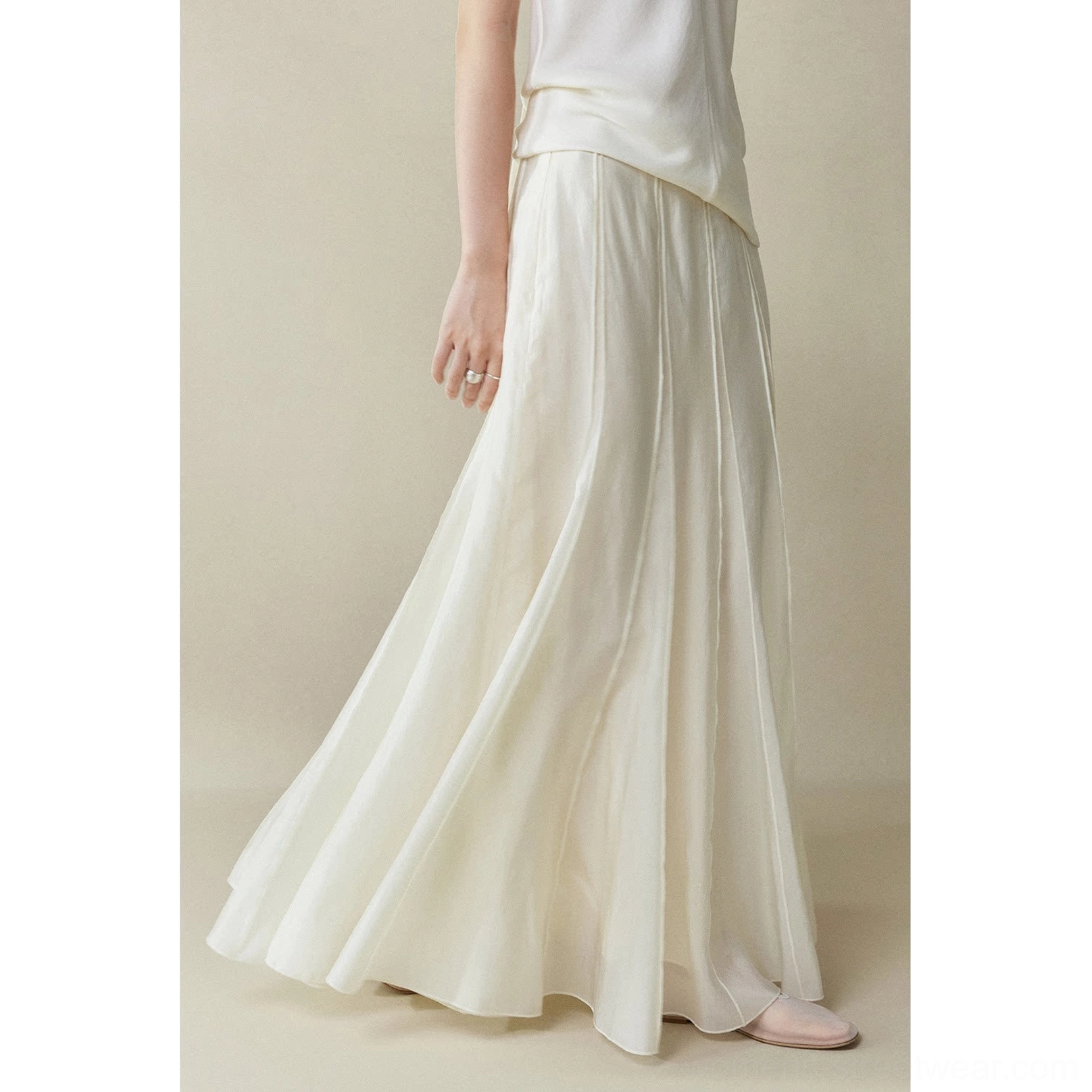 Moon White cupro fishtail maxi skirt shown from a low side view with flowing movement, vertical panel seams, and a clean minimalist studio background