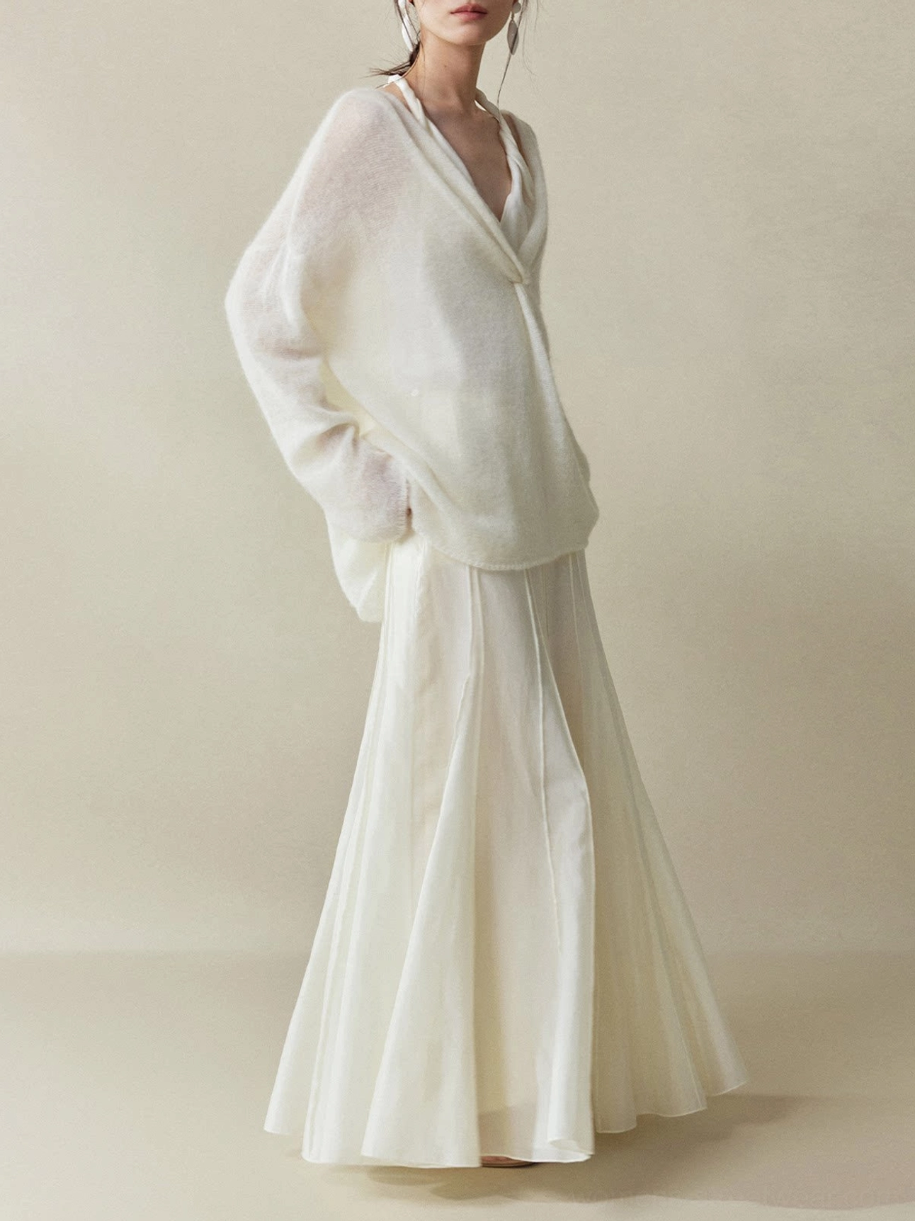 Moon White paneled fishtail maxi skirt shown in side profile with hands in pockets, vertical seams, and a flowing silky cupro-blend finish