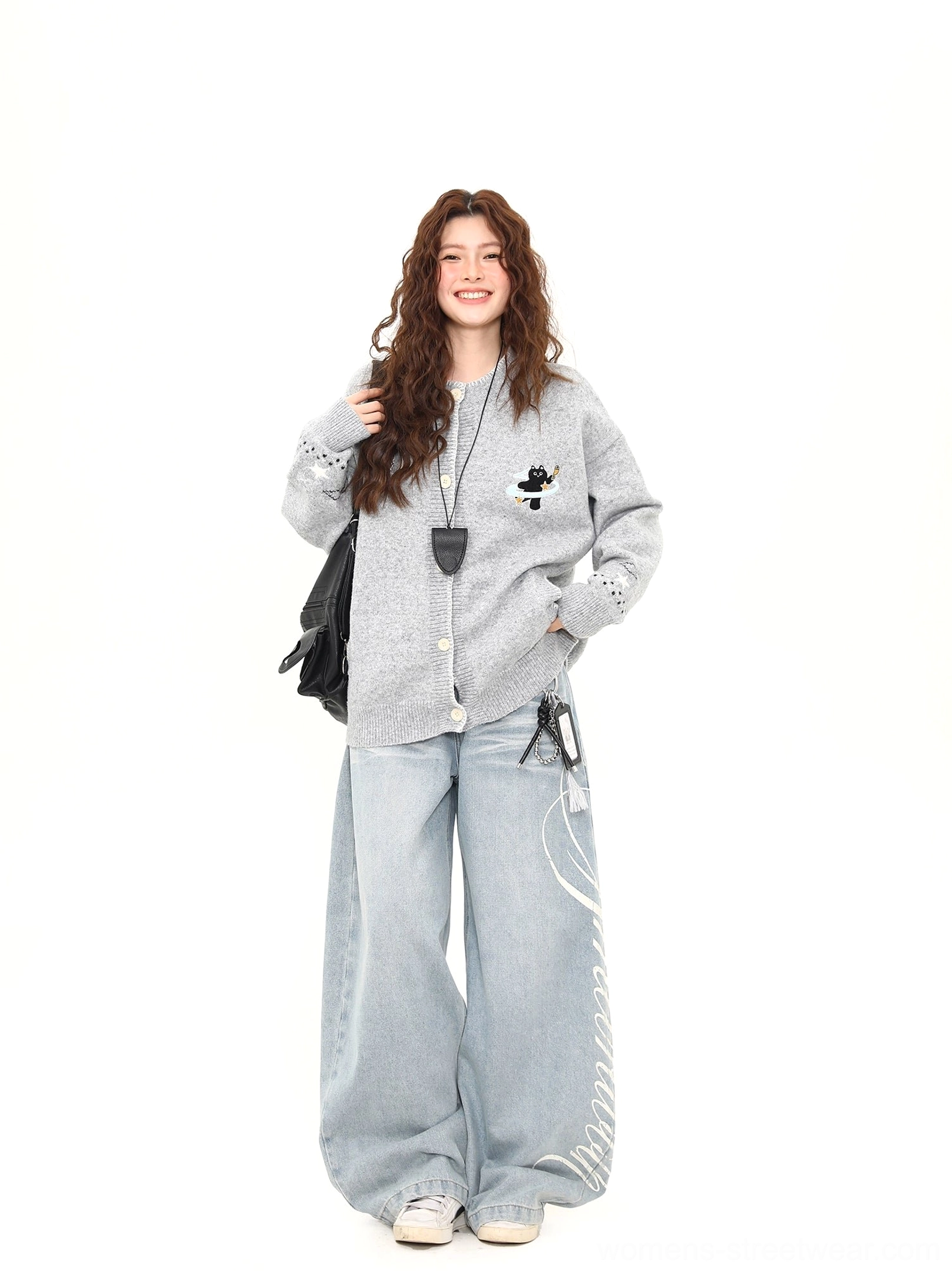 Full front view of a heather grey Moonlight Kitty embroidered cardigan with black shoulder bag, front button closure, ribbed trims, and wide-leg jeans
