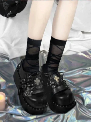 Black patent multi-buckle Gothic platform Mary Jane shoes worn with crisscross black socks on holographic silver fabric