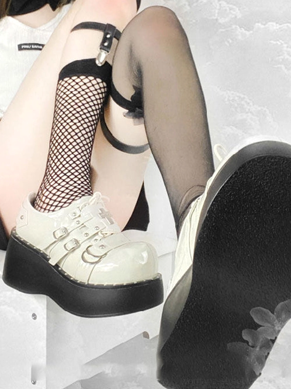 Back view of white patent Gothic platform Mary Jane shoes worn with fishnet tights, showing thick treaded platform soles