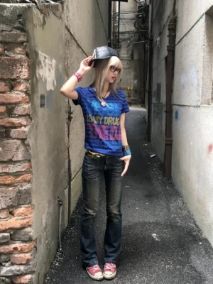 Full body front view of model wearing deep blue Music Is My Drug rhinestone striped V-neck tee with jeans