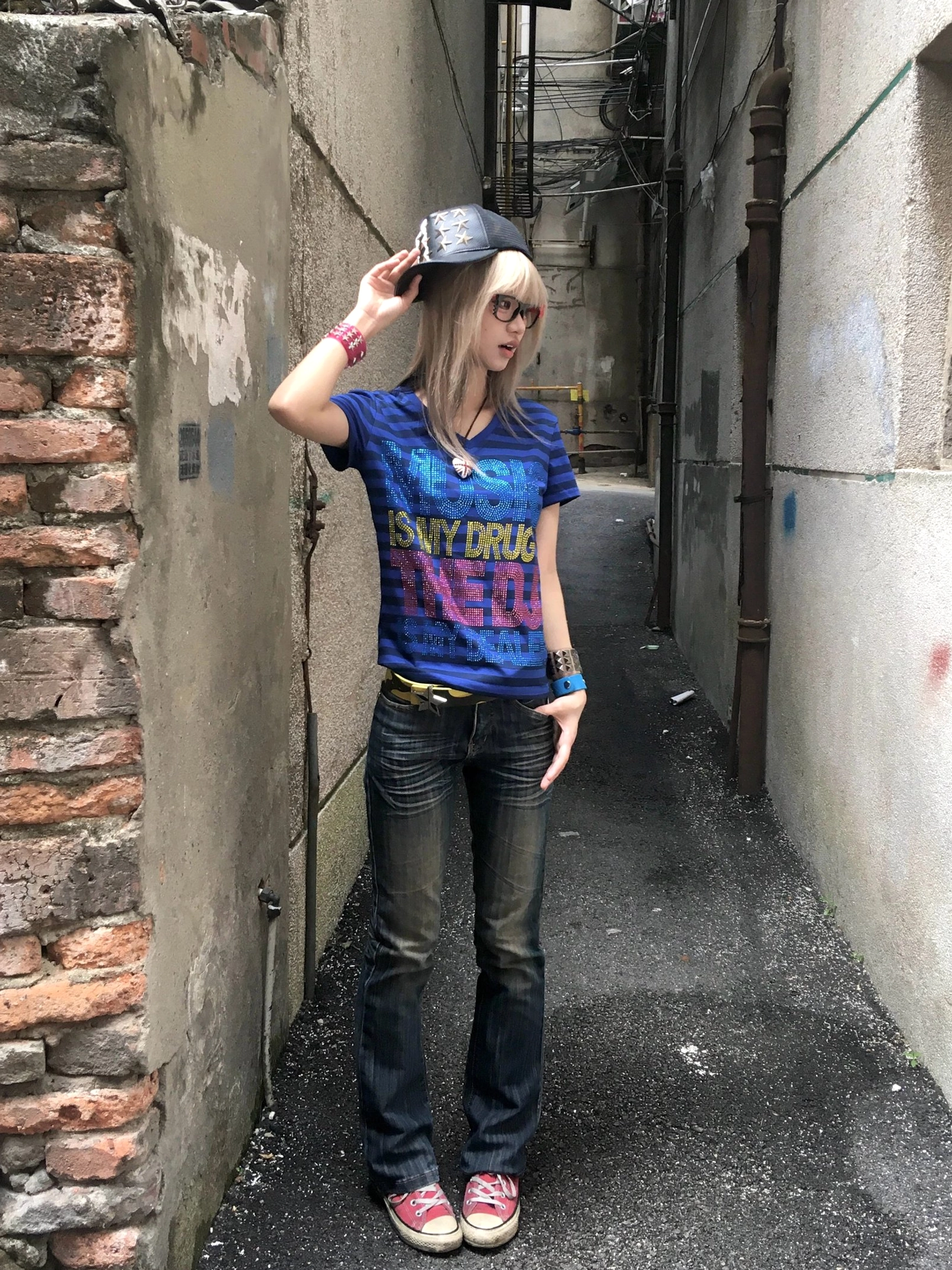 Full body front view of model wearing deep blue Music Is My Drug rhinestone striped V-neck tee with jeans