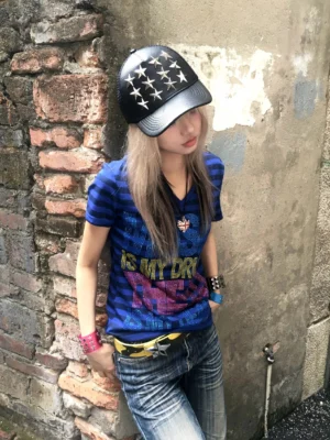 Front close-up of the Music Is My Drug rhinestone striped V-neck tee styled with jeans and a cap