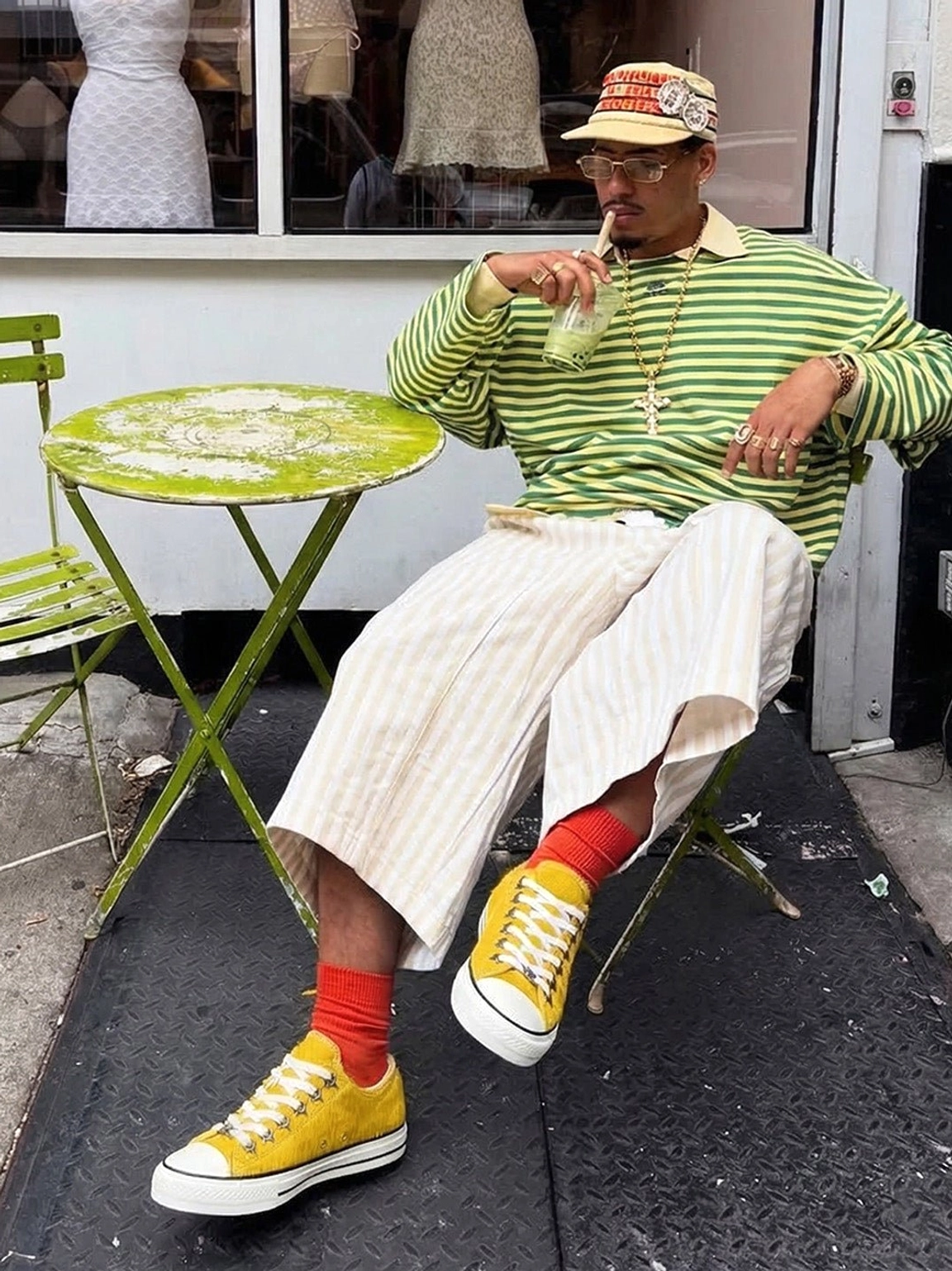 Mustard yellow cowhide streetwear sneakers styled with wide-leg pants, red socks, striped top, and retro cap in an outdoor fashion look