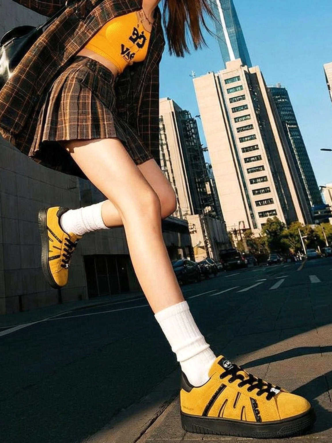 Model wearing mustard yellow suede platform skate sneakers with white crew socks and plaid skirt streetwear outfit