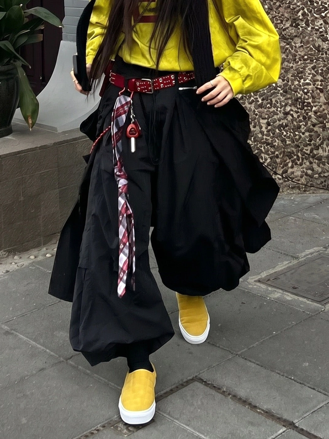 Pair of mustard yellow quilted slip-on sneaker mules worn while walking in wide black streetwear pants