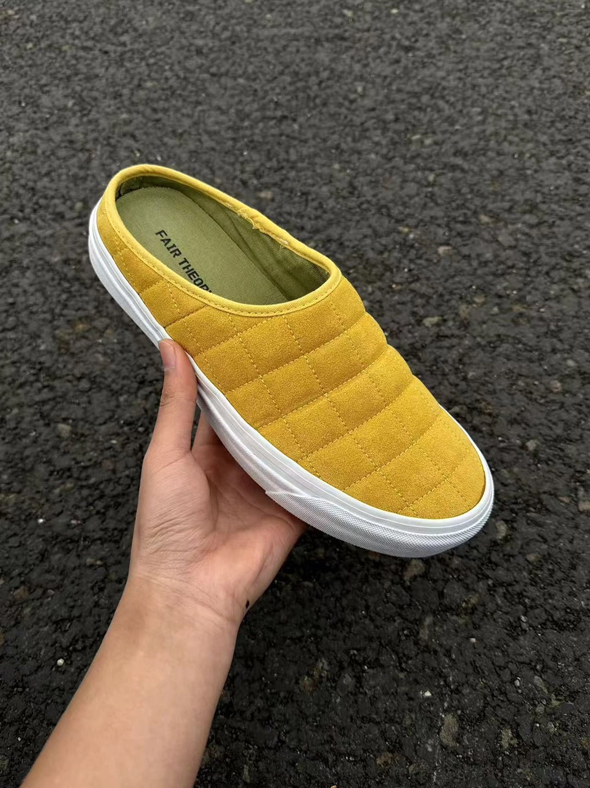 Close-up of mustard yellow quilted slip-on sneaker mule showing padded diamond texture interior and white rubber sole
