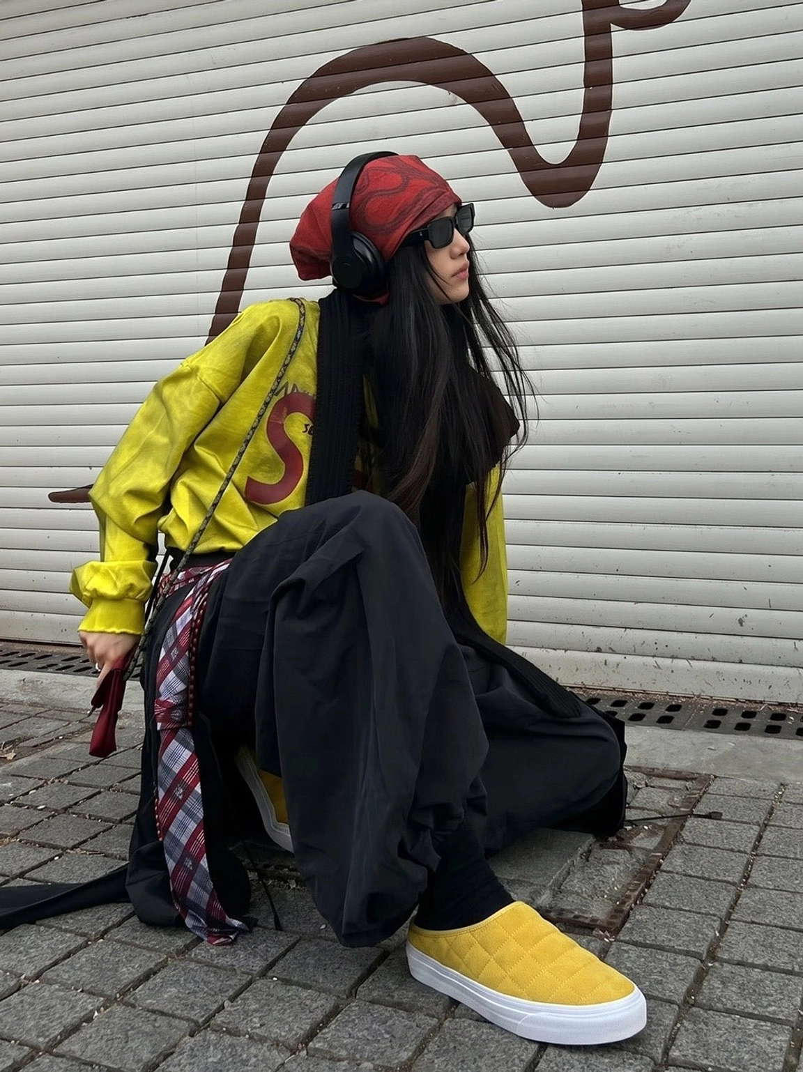 Mustard yellow quilted sneaker mules worn with wide black pants in a colorful urban streetwear outfit