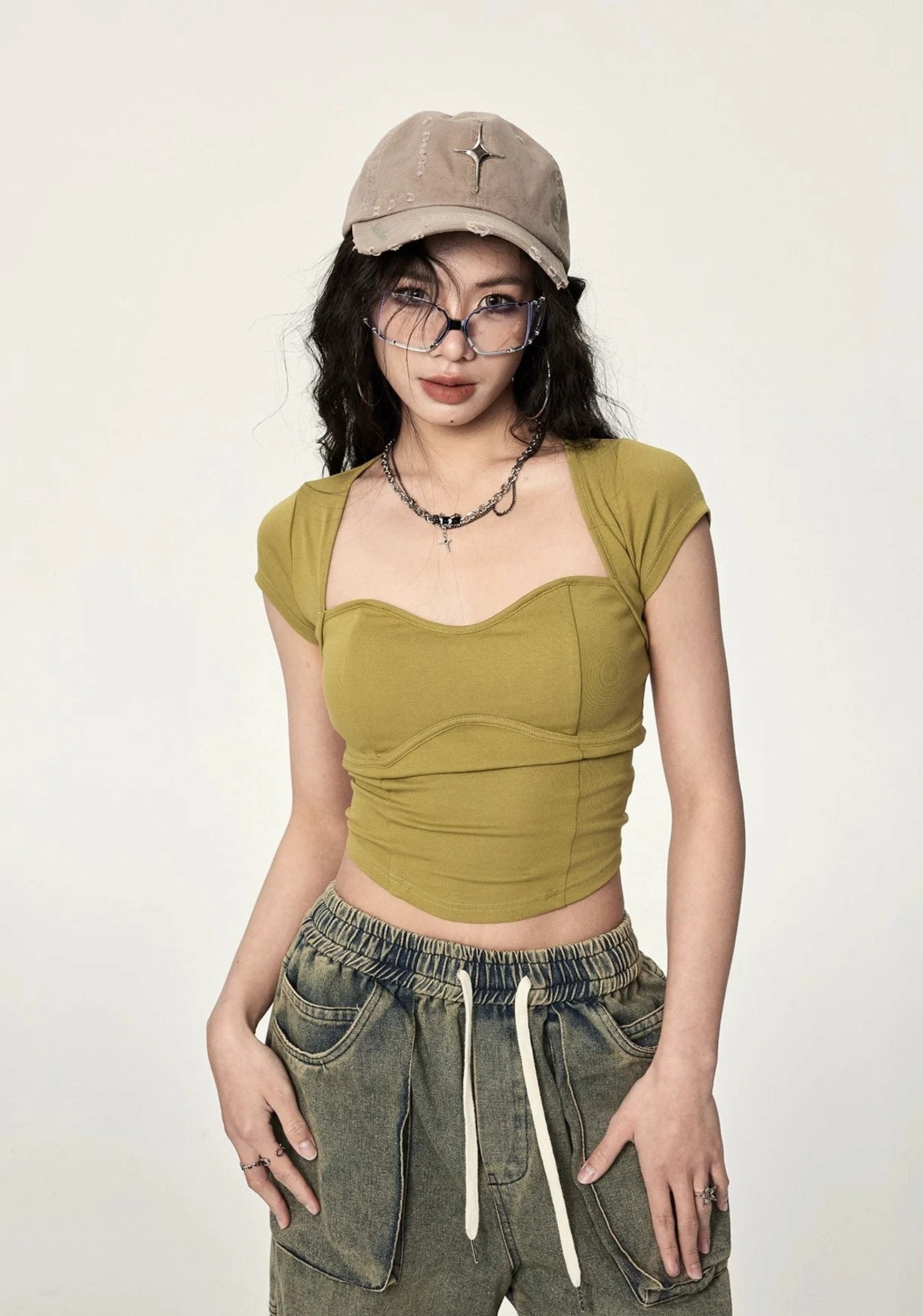 Mustard yellow ribbed twist open back crop top shown from the front with sweetheart neckline, fitted silhouette, cropped hem, layered necklace, and retro denim