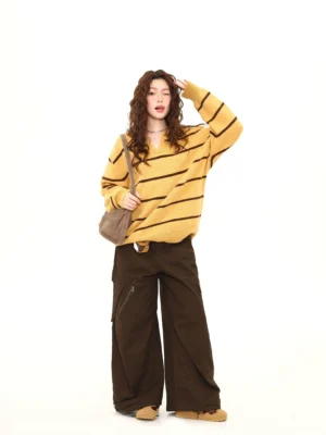 Mustard yellow striped oversized knit polo sweater in three quarter front view styled with brown cargo pants and canvas shoulder bag