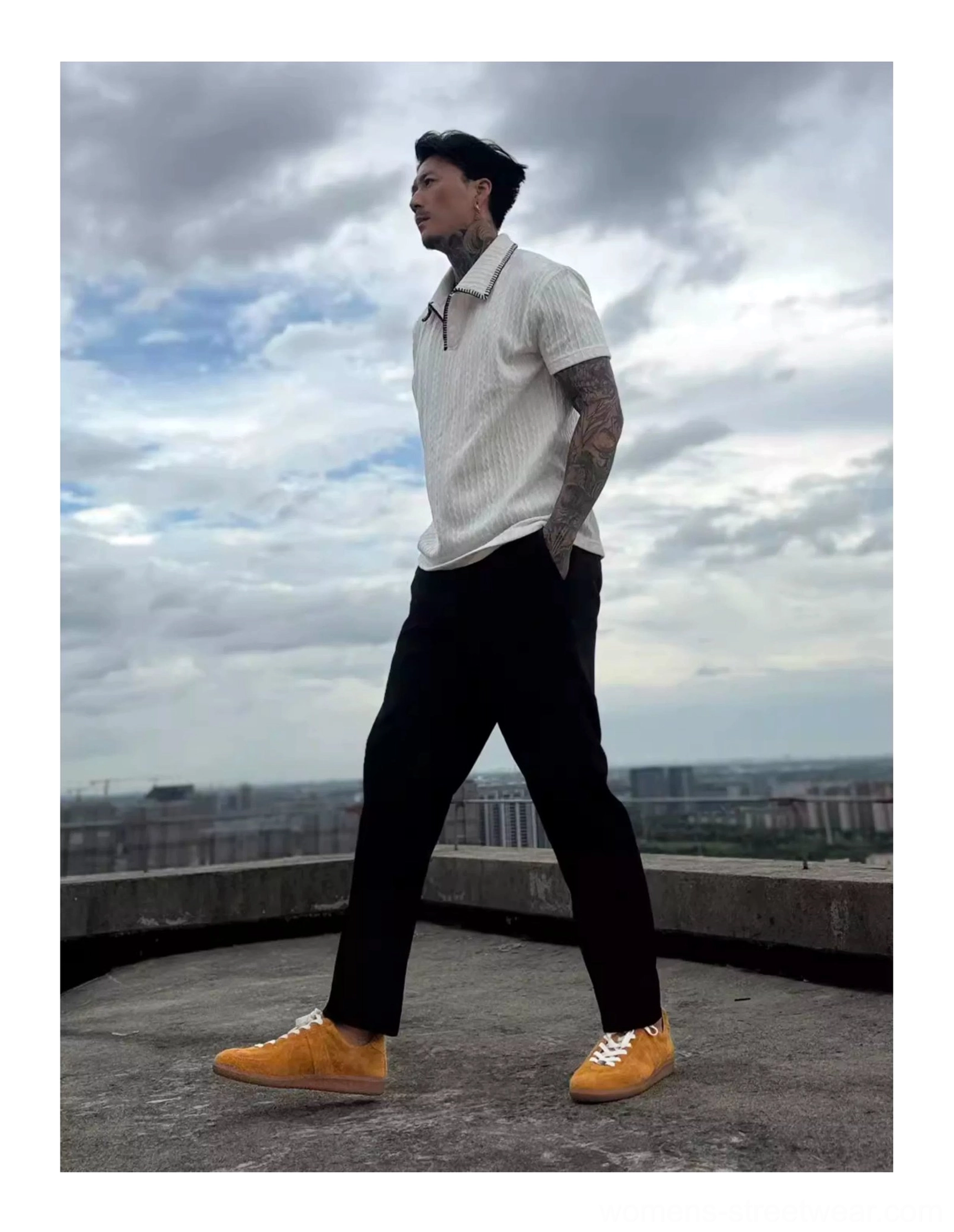 Mustard yellow vintage suede streetwear sneakers worn with black tailored trousers and a white polo shirt on an urban rooftop