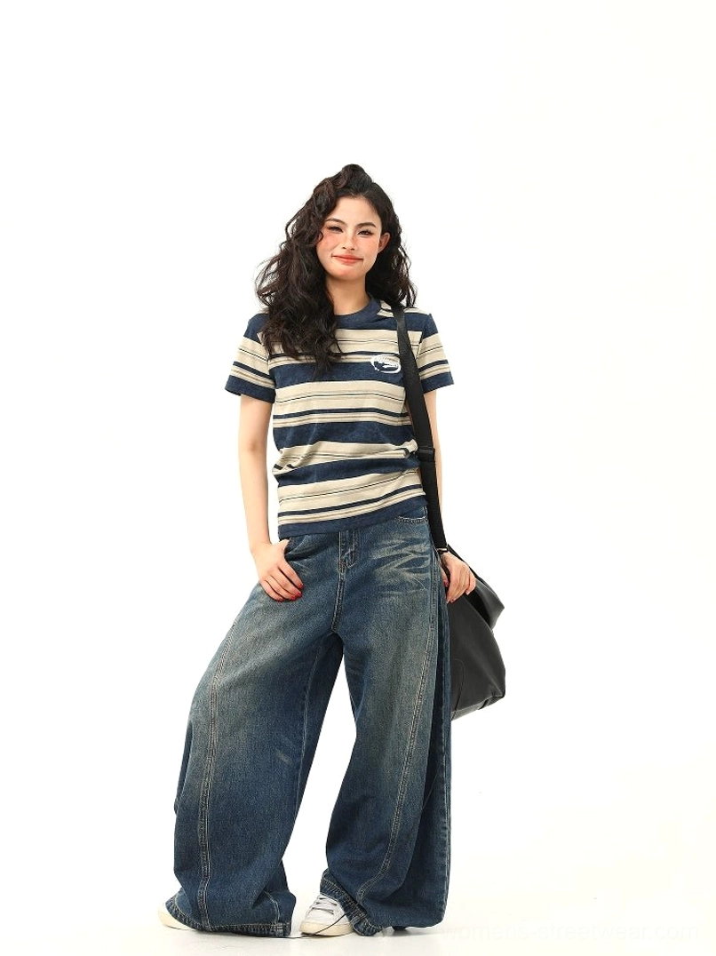 Full body outfit featuring navy and beige striped crewneck T-shirt with wide-leg jeans white sneakers and shoulder bag