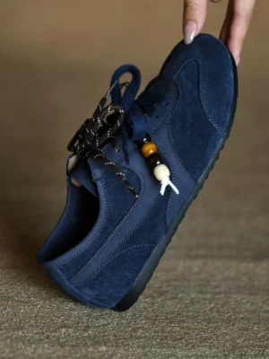 Navy blue suede beaded retro sneaker in an overhead view with striped decorative laces and handmade-style bead charms