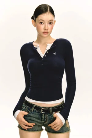 Navy blue layered Henley long sleeve streetwear top with white contrast trim, ribbed stretch fabric, and slim fit styled with denim shorts