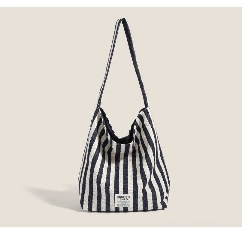 Navy blue and off-white candy stripe canvas hobo shoulder bag with wide strap and relaxed streetwear market tote shape