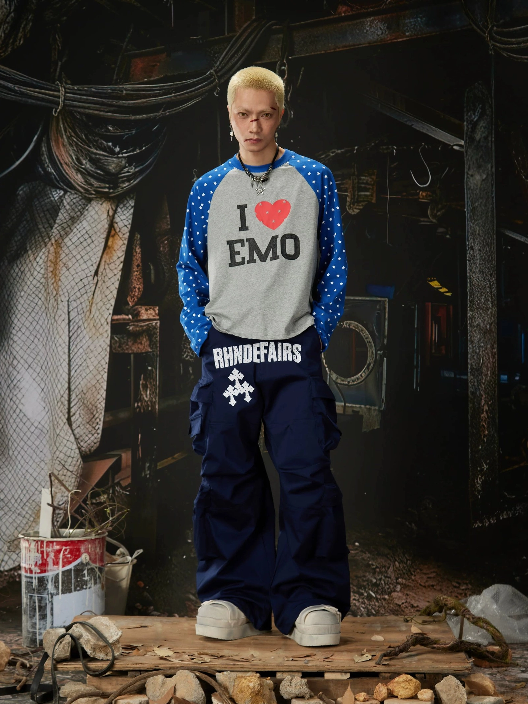 Navy blue stacked pocket streetwear cargo pants styled with graphic raglan long sleeve shirt in industrial studio
