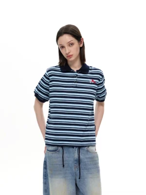Female model wearing navy blue striped retro polo shirt with embroidered chest detail front view