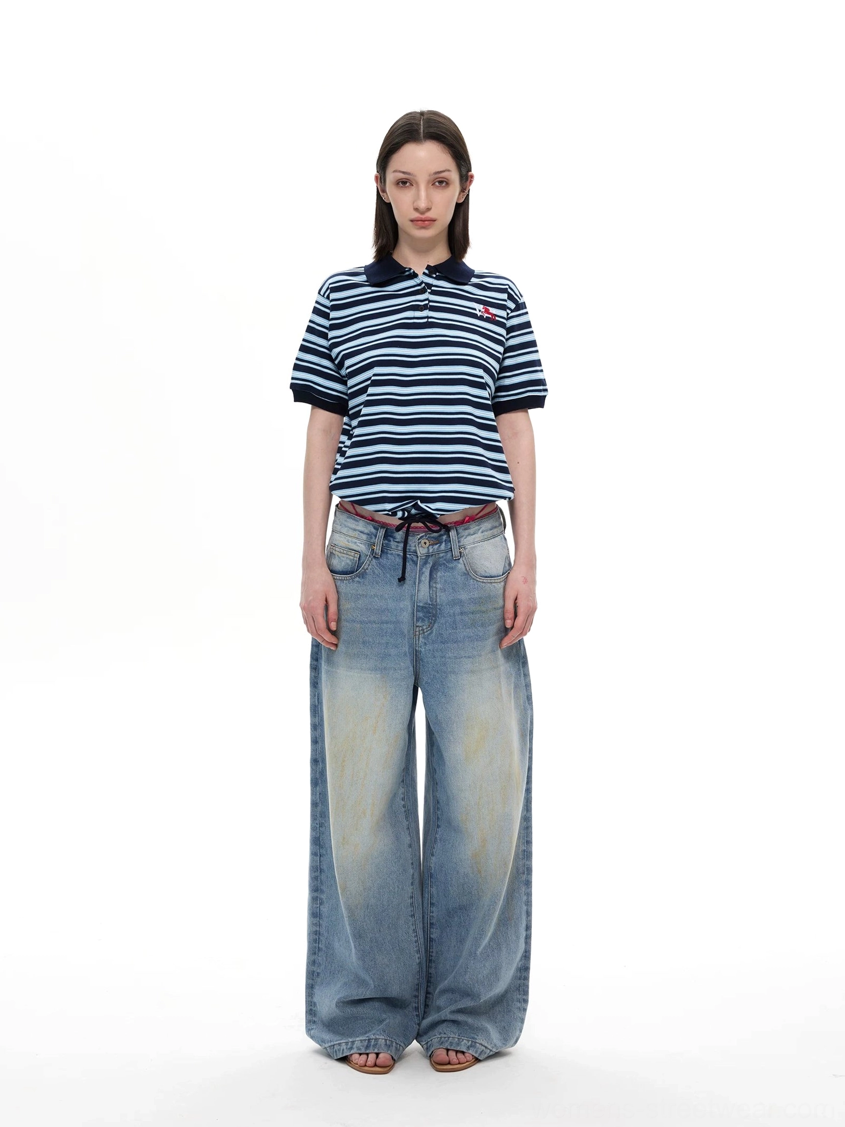 Navy blue striped short sleeve polo shirt styled with washed wide leg denim jeans full body front view