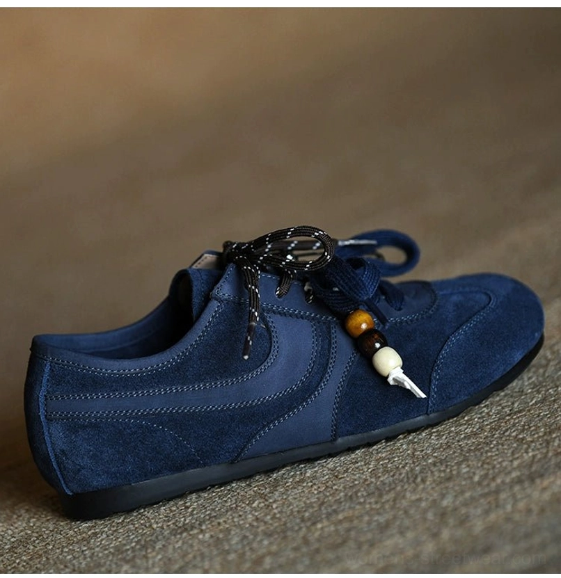Side view of a navy blue suede casual sneaker with curved panels and flexible flat black outsole