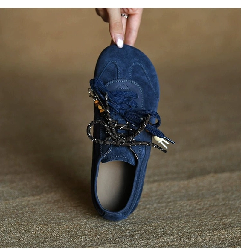 Detailed angled view of a navy blue suede retro sneaker showing neat upper stitching and structured vamp construction